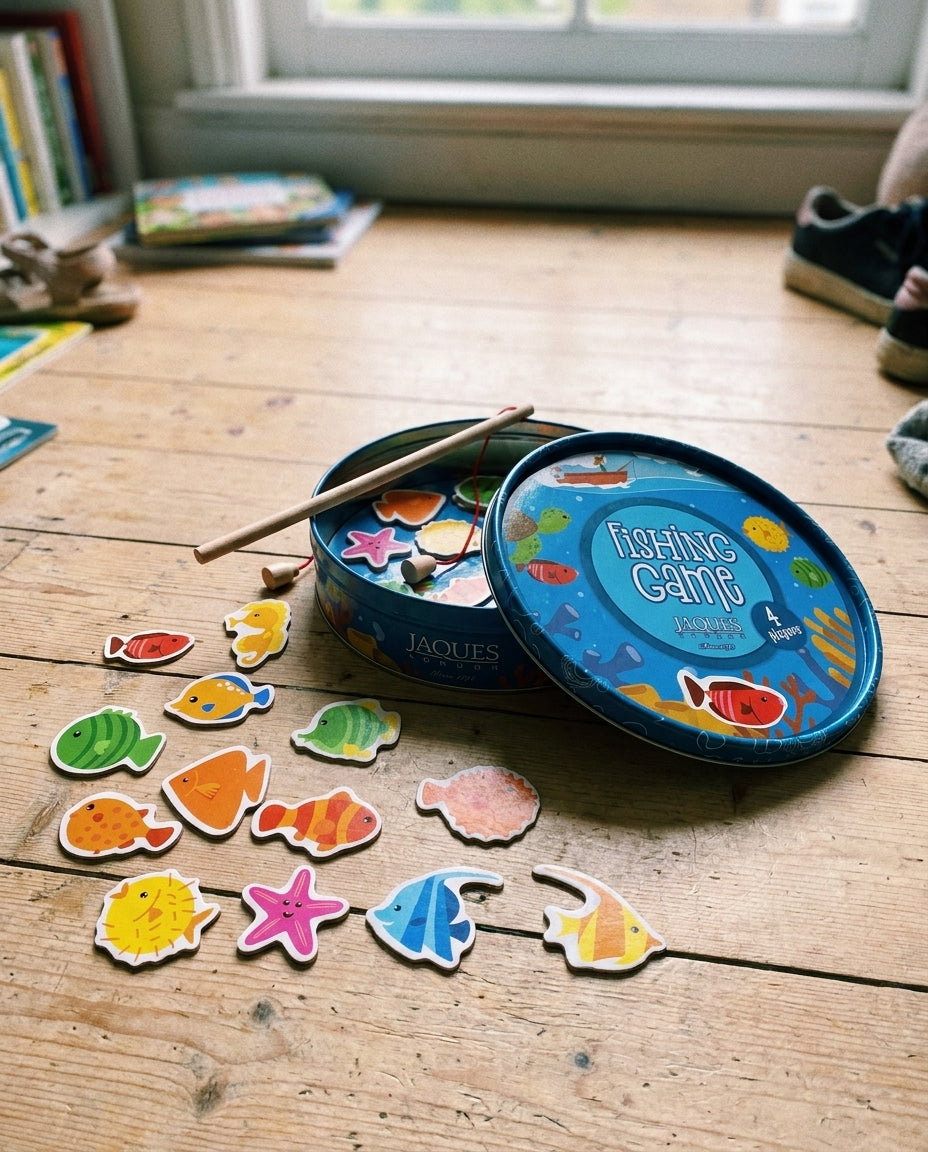 Jaques Magnetic Fishing Game mid-play on a wooden floor — blue tin, colourful wooden sea-creatures and a rod