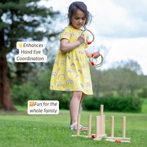 Child in a yellow dress playing with wooden toys outdoors.  