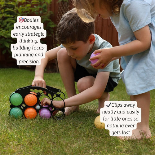 Two children crouch on the ground, engaged in a game with colorful balls. 
