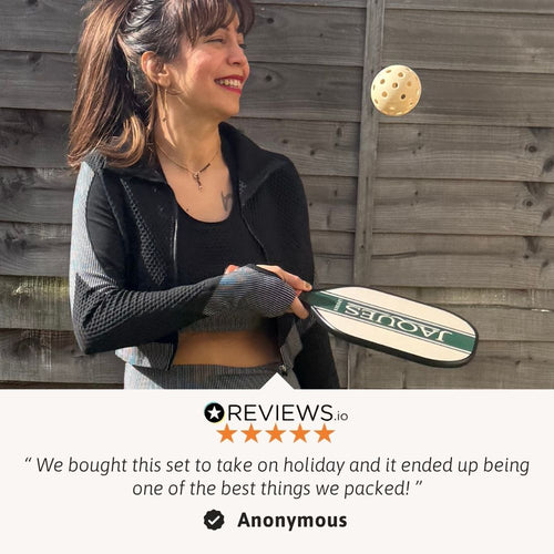 Woman holding a pickleball paddle with a wooden fence background 
