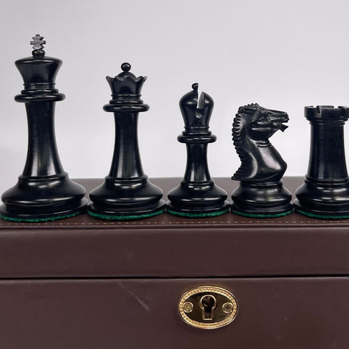 Set of black chess pieces on a brown chessboard with a gold lock. 