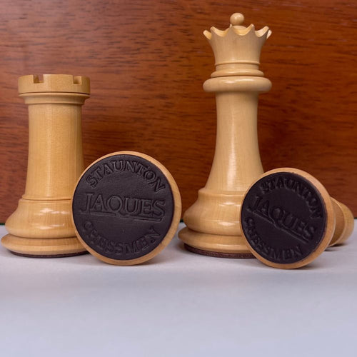 Wooden chess pieces with Staunton Jaques branding on a wooden background 