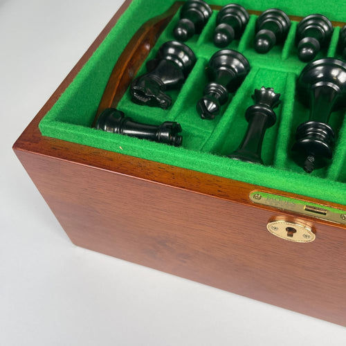 Black chess pieces in a wooden box with green felt lining 