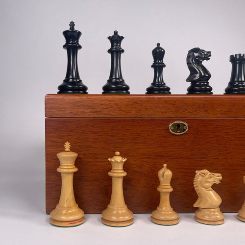 Set of black and white chess pieces with a wooden box on a light grey background 