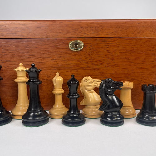 Set of chess pieces in front of a wooden chessboard box 