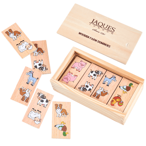 Wooden farm domino game set by Jaques London, showing the open wooden box with animal-themed domino tiles and several loose tiles arranged on a solid green background. [fill]