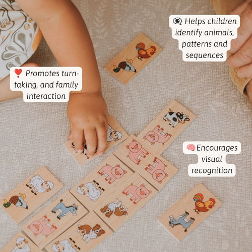 A child's hands arranging small wooden animal cards on a textured beige fabric surface. The cards show illustrated farm and pet animals such as cows, pigs, sheep, horses, a rooster, and a squirrel. 