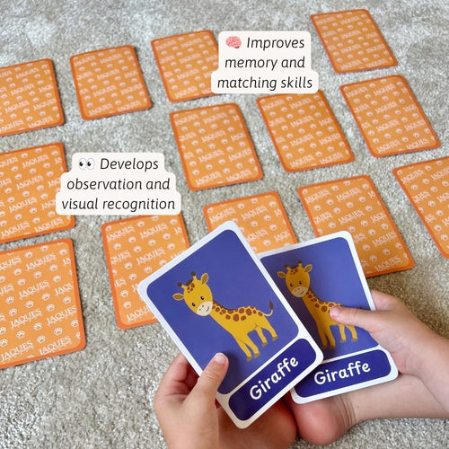 A person's hands holding two matching 'Giraffe' cards from a Jaques board game set, with many orange patterned cards spread out on a grey carpet in the background. White text callouts mention improving memory and matching skills and developing observation and visual recognition.