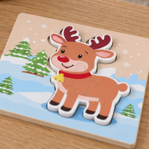 A wooden children's puzzle board featuring a cartoon reindeer with red antlers and a red nose, standing in a snowy winter scene with green trees. The puzzle is photographed on a light wood tabletop.