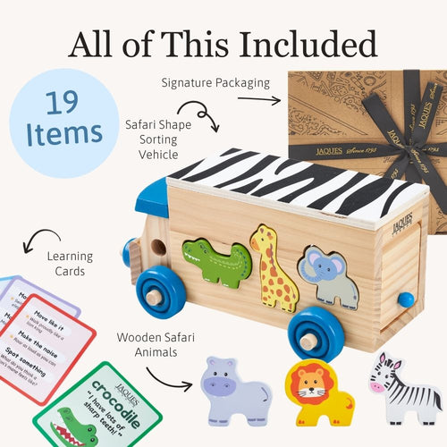 Wooden safari-themed sorting vehicle toy set shown with included accessories on a light beige background. The main product is a natural wood box shaped like a safari truck with blue wheels, zebra-print top, and animal cutouts (crocodile, giraffe, elephant, rhino, lion, zebra).