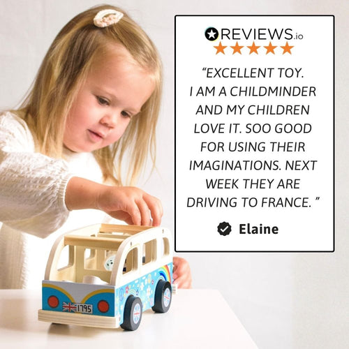 A young girl with blonde hair is playing with a wooden toy bus on a white table. On the right side of the image is a review card with a five-star rating and a testimonial quote from Elaine. 