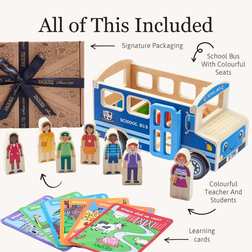 A children's educational toy set titled 'All of This Included' on a light beige background. The set includes a blue and wood school bus, several wooden character figures, colorful learning cards, and a branded gift box with a dark ribbon. 
