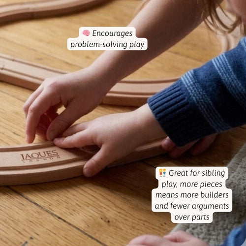 Children playing with wooden train tracks on a wooden surface