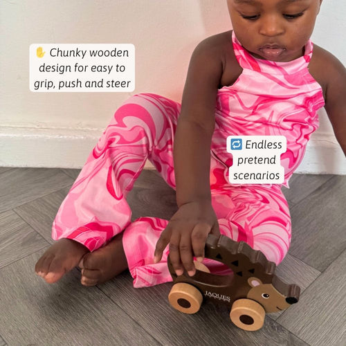 Child playing with a wooden toy hedgehog on a wooden floor. 