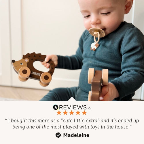 Baby playing with wooden toys, holding a hedgehog-shaped toy.