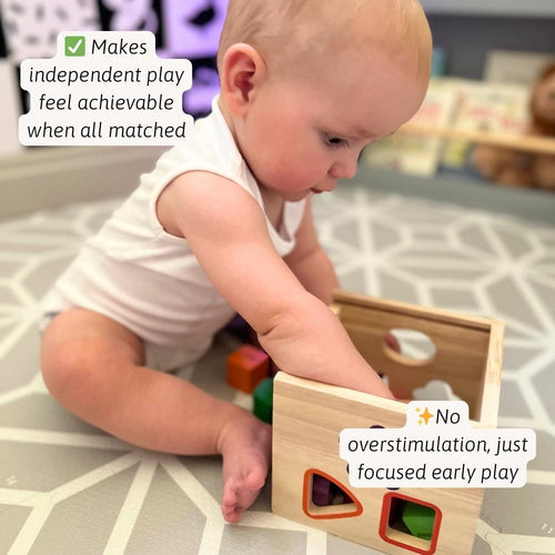 Toddler using wooden shape sorter cube for independent play 
