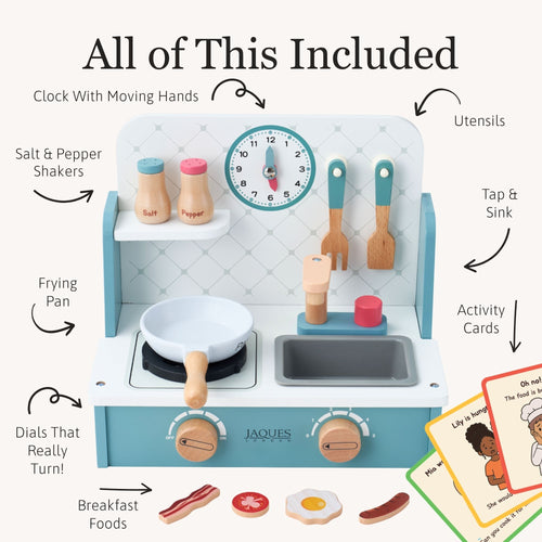 A children's play kitchen set shown with labeled callouts and included accessories on a cream background. The main product is a light aqua and white toy stove with wooden knobs, a clock, utensils, frying pan, sink, and shelf. 