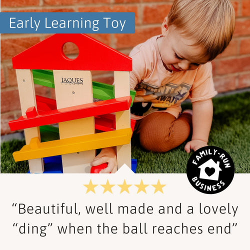 Toddler playing with Jaques of London colourful wooden ramp toy – encouraging early learning, coordination, and sensory play development. 
