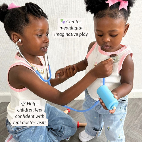 Two young girls playing with a toy stethoscope and syringe on a wooden floor.  