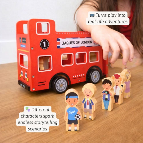 Red toy bus with wooden figures on a wooden surface, labelled 'Jaques of London'. 