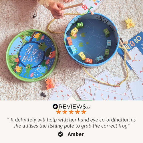 Top-down view of the frog fishing game set with lid removed, showing wooden frogs, number cards and fishing rods, with a customer review quote below 