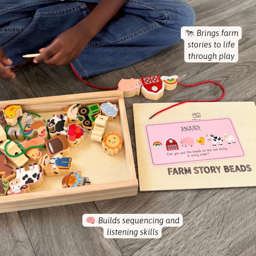 A child's hands and legs are visible while playing with a wooden farm-themed bead board and matching story beads on a grey wood floor. The set includes colourful wooden farm animal and object beads in a tray, a red string with bead pieces, and a printed story board titled 'Farm Story Beads'.