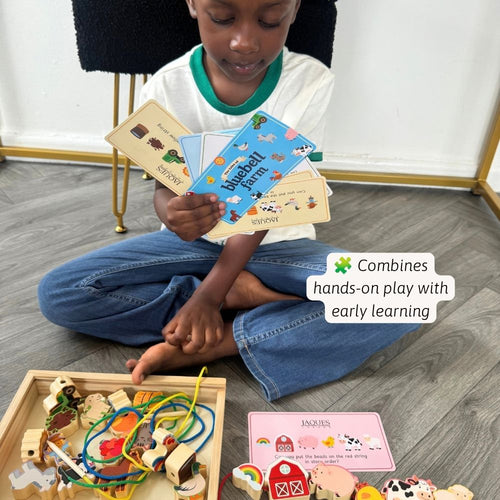 A young child sits cross-legged on a wood floor, holding colorful educational cards. A wooden tray of toy blocks and learning pieces is spread out in front, with a text overlay that reads 'Combines hands-on play with early learning.