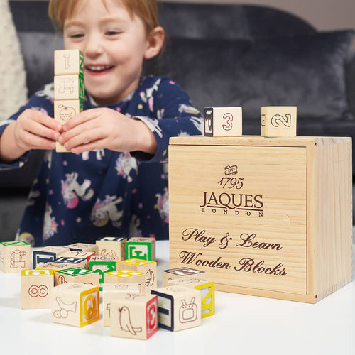 Child playing with wooden blocks from Jaques of London, with a focus on educational toys. 