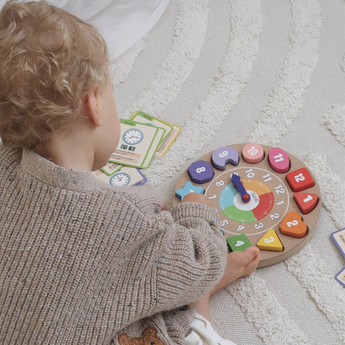 Toddler playing with the Jaques wooden teaching clock and time telling flashcards during floor play 