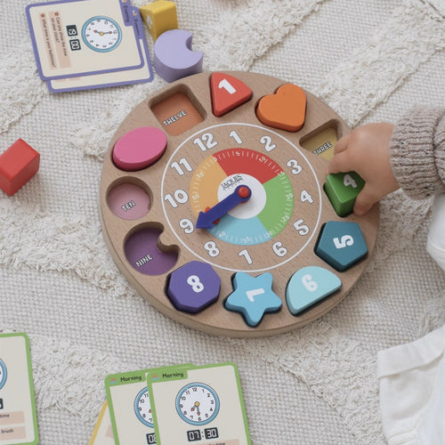 Childs hand placing the number four shape into the Jaques wooden shape sorting clock toy 
