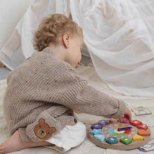 Toddler reaching to set the hands on the Jaques of London wooden time telling clock 