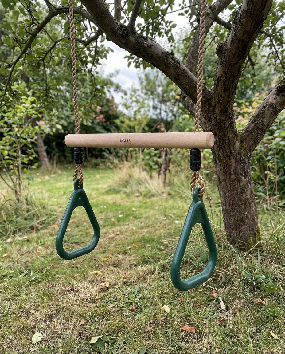 Child swinging on the wooden trapeze bar in a garden